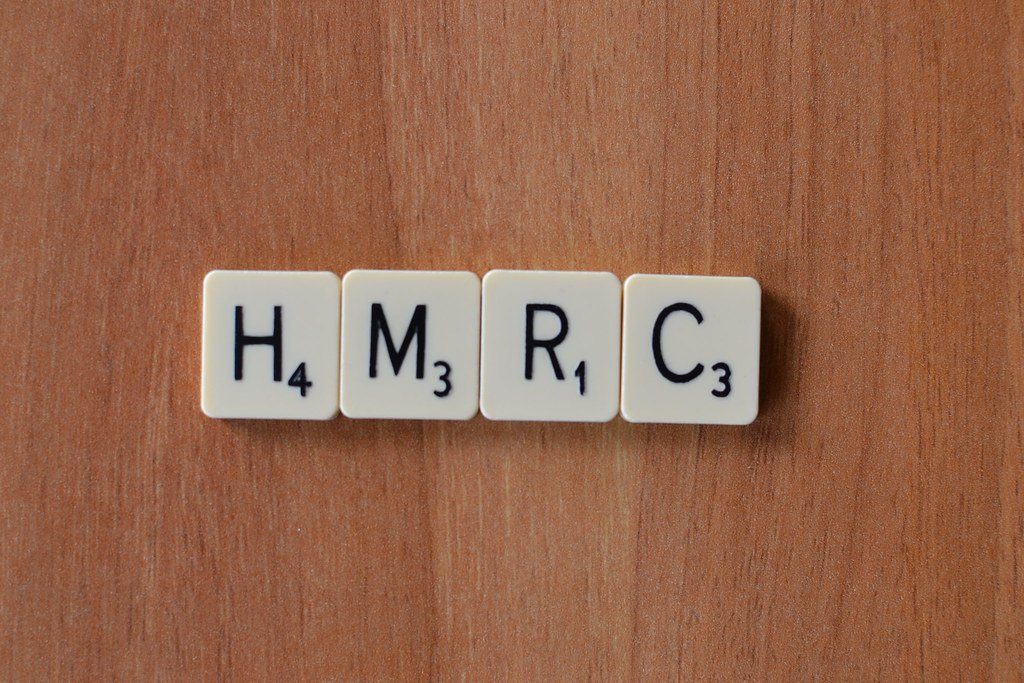 Letter tiles spelling HMRC on a wooden table