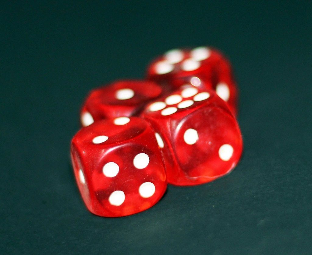 A pile of red translucent dice on a green table