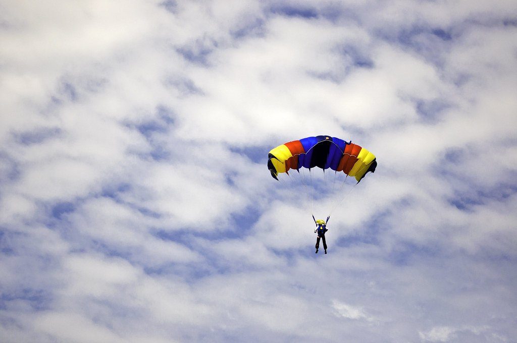 A colourful parachute drifting through a cloudy sky
