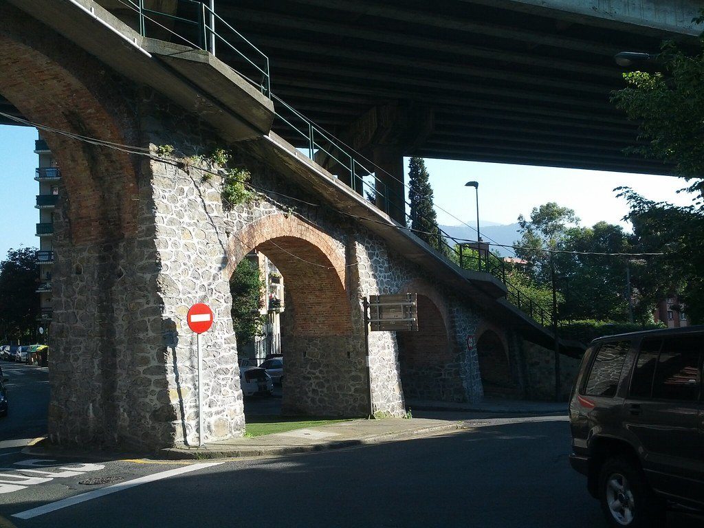 A road running beneath an old stone viaduct